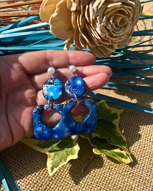 Handmade blue resin polymer clay drop earrings with pearl studs held in hand